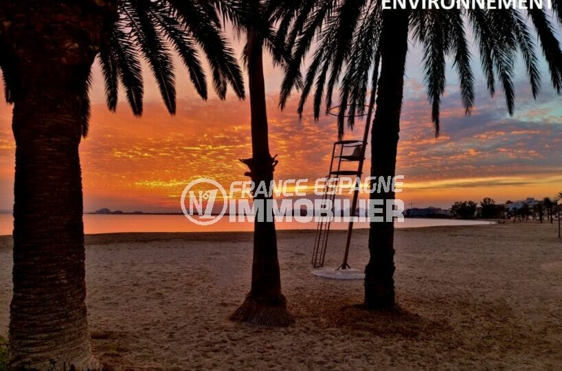douce soirée sur la plage de rosas avec coucher de soleil sur les palmiers